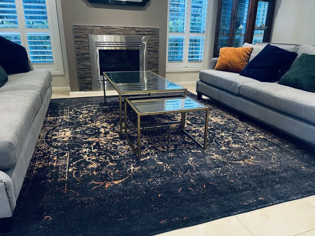 Navy and gold rug between grey sofas in front of a fireplace